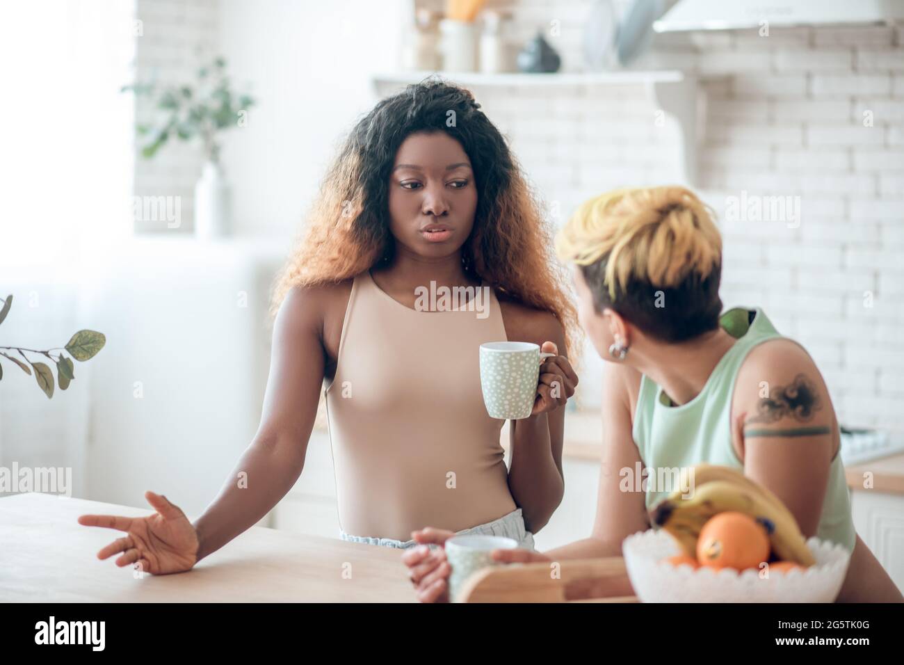 Reasoning african american woman with coffee and listening girlfriend Stock Photo