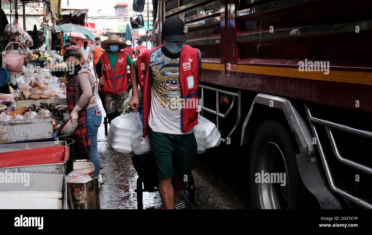 Man wearing Red Vest with Hand Truck Klong Toey Market Wholesale Wet Market Bangkok Thailand largest food distribution center in Southeast Asia Stock Photo