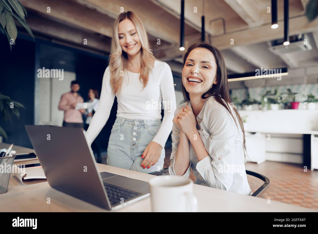 Two young happy businesswomen celebrating project success in office ...