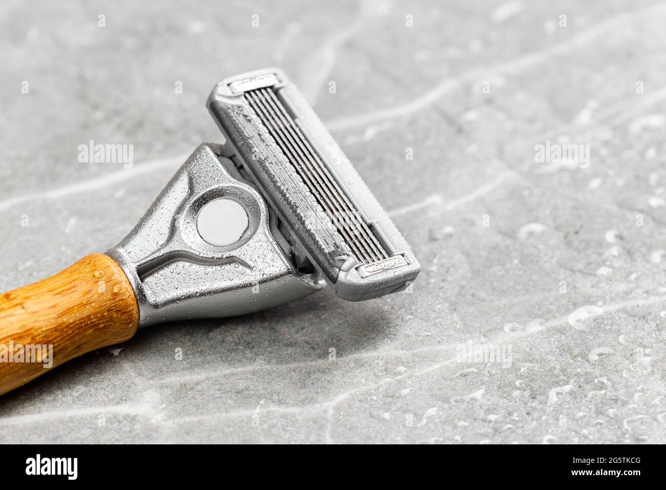 Wet shaving Razor with five blades head and wooden handle on a grey marble background. Macro shot Stock Photo