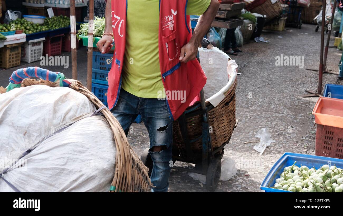 Man wearing Red Vest with Hand Truck Klong Toey Market Wholesale Wet Market Bangkok Thailand largest food distribution center in Southeast Asia Stock Photo