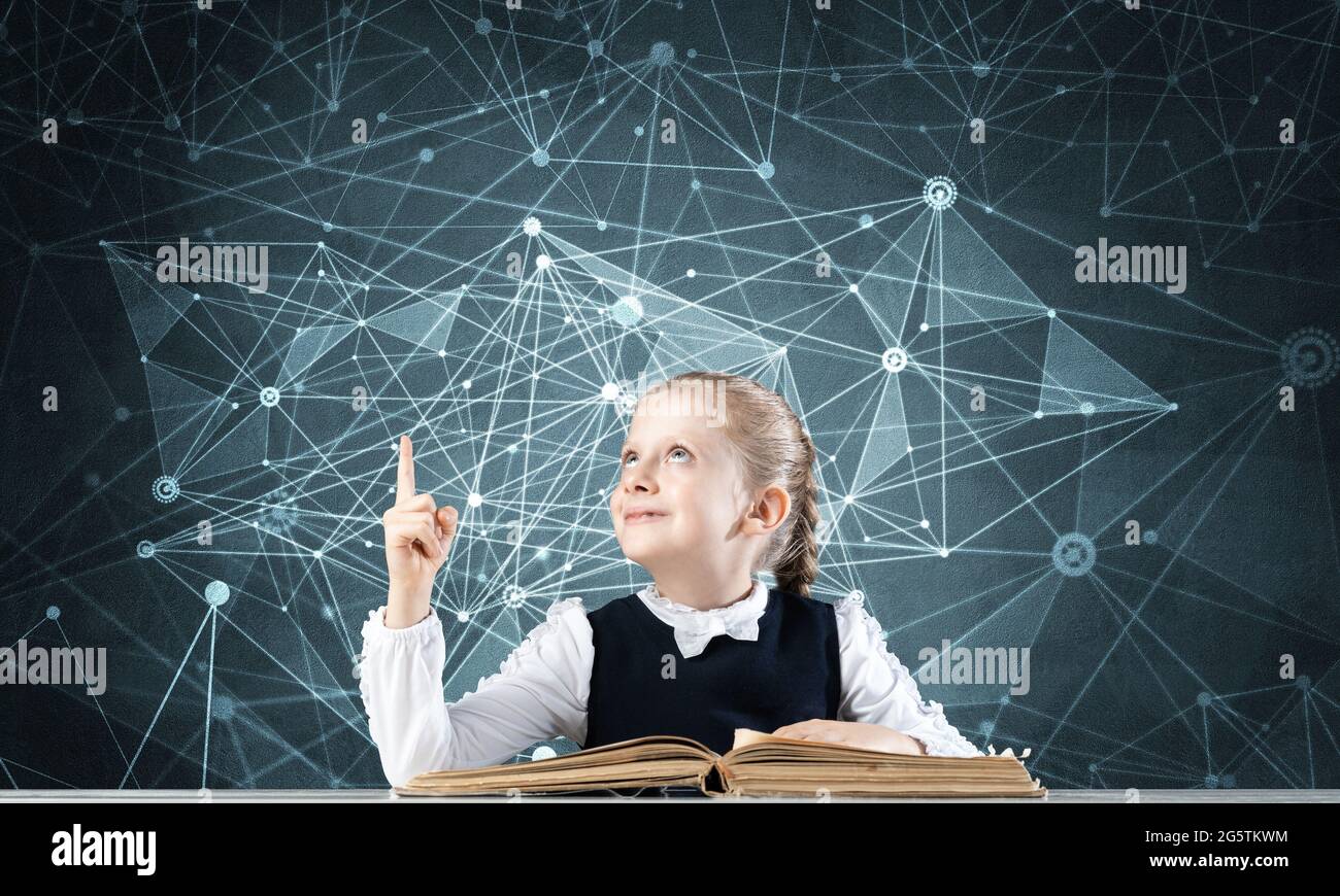 Smiling little girl sitting at desk with open book Stock Photo - Alamy