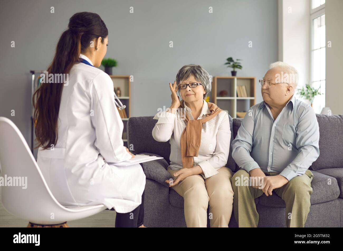 Doctor listening to senior patients sharing their health concerns during home visit Stock Photo