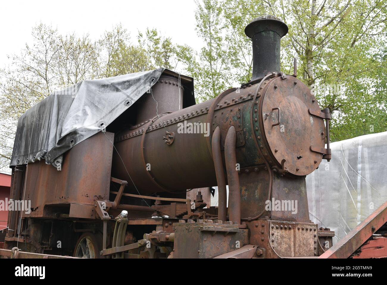 Front-end view on discarded rusty freight steam locomotive loaded on old wagon. Stock Photo