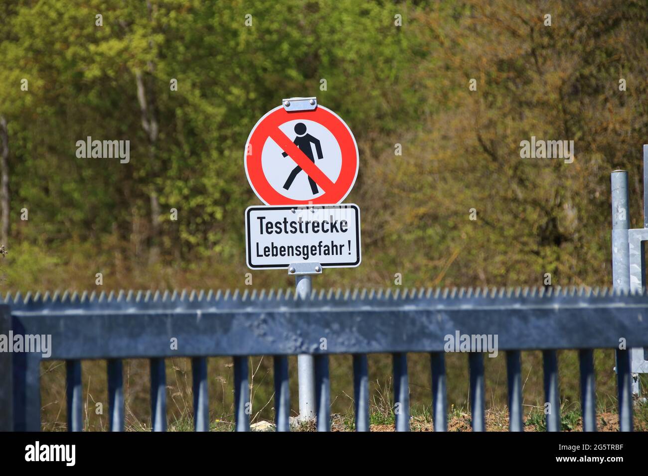 Traffic sign prohibiting pedestrians with reference to a test track and danger to life Stock Photo
