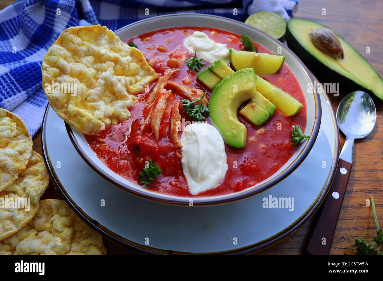 Chicken tortilla chili soup with beans, avocado, lime, . Mexican traditional dish Stock Photo
