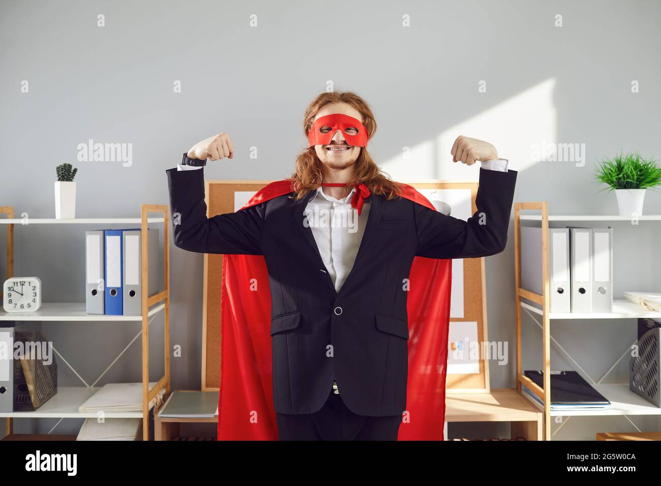 Funny office worker in red superhero mask and cape demonstrating can-do attitude Stock Photo