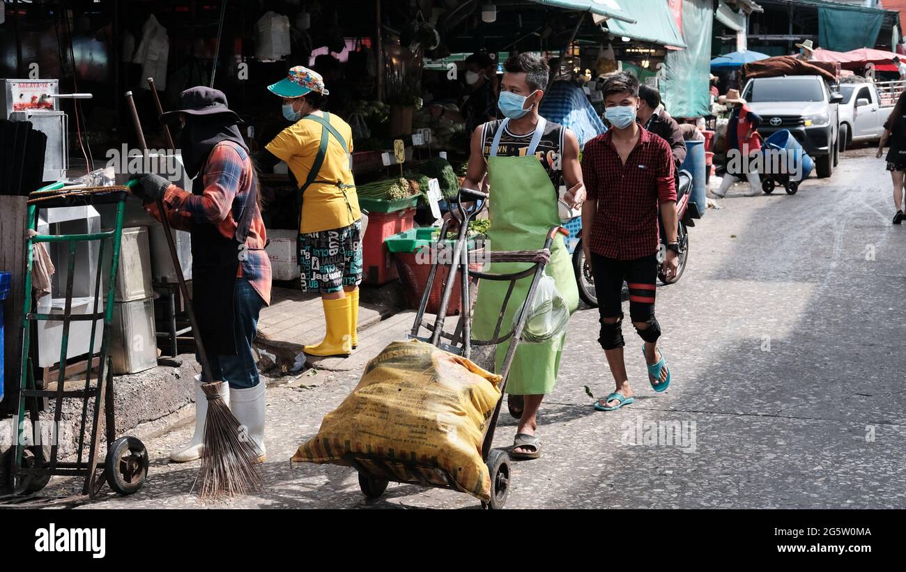 Man wearing green apron pushing hand truck Klong Toey Market Wholesale Wet Market Bangkok Thailand largest food distribution center in Southeast Asia Stock Photo