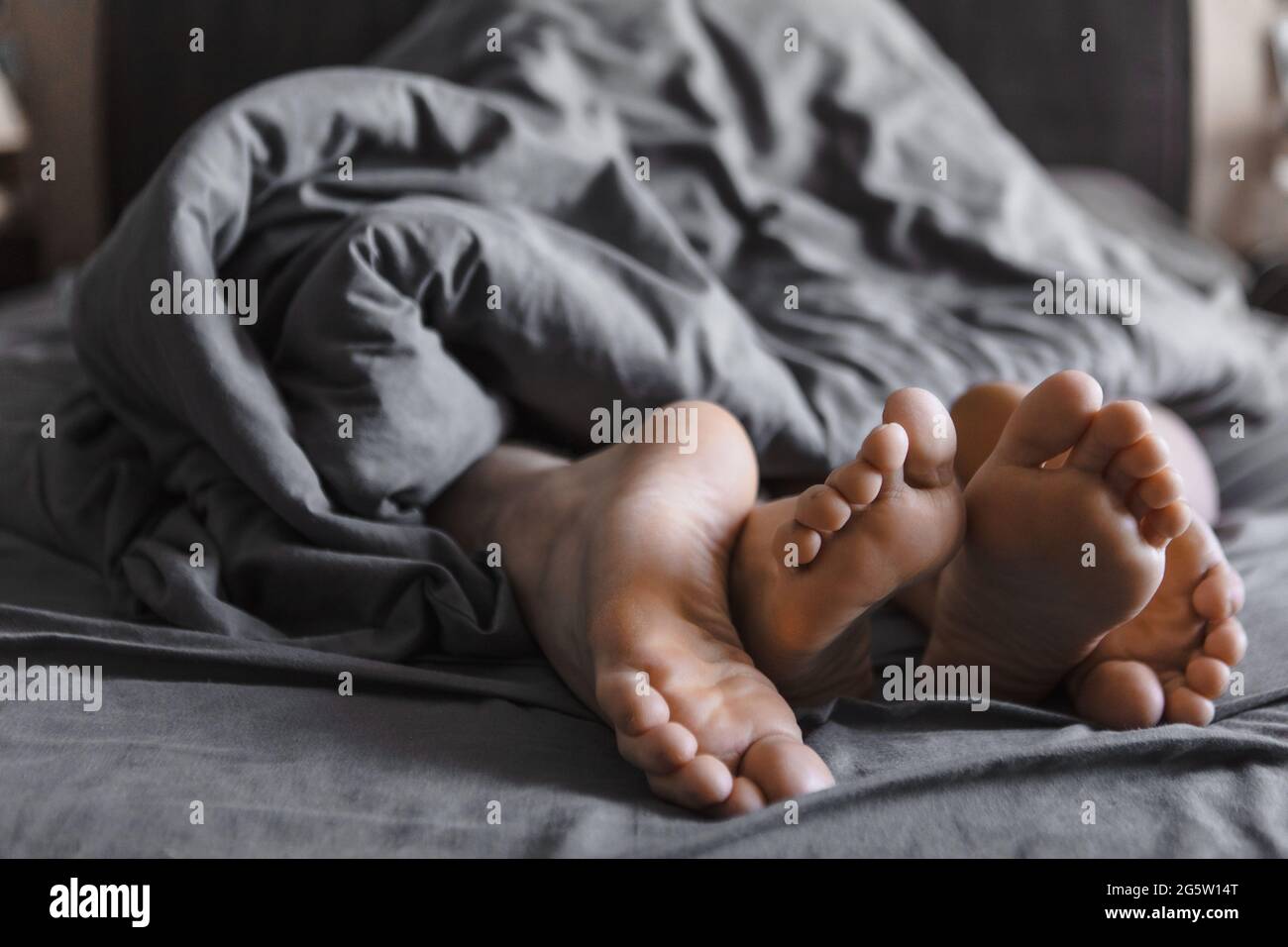 couple feet under the blanket in bed with grey sheets close up copy