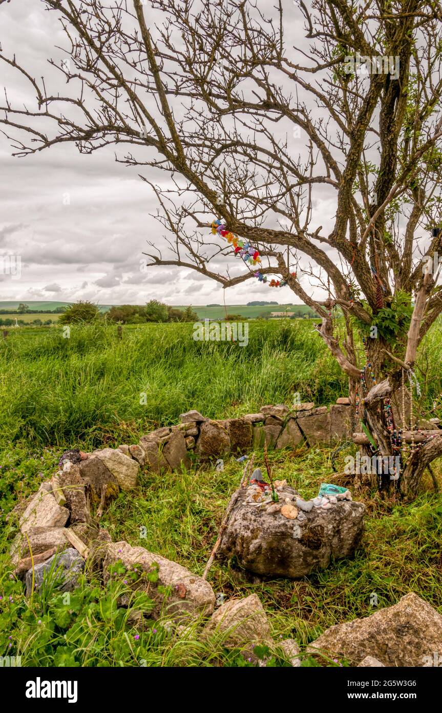 A small shrine with ritual offerings at the base of a clootie tree on the Ridgeway near Avebury in Wiltshire. Stock Photo