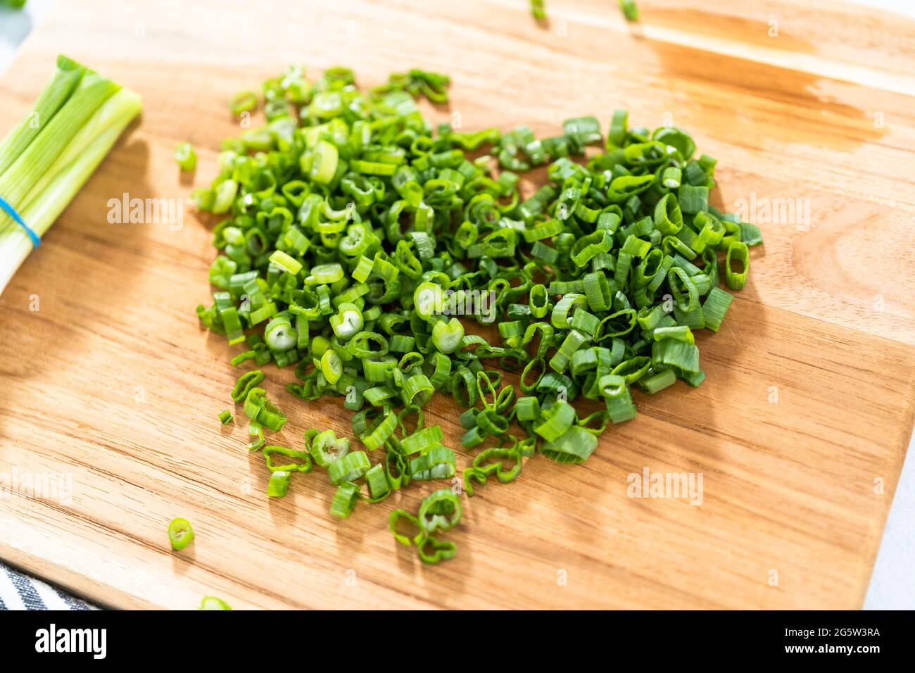 Chopping organic green onions on a wood cutting board Stock Photo - Alamy