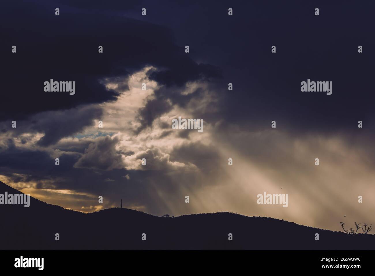 Intense Sun Rays thick stormy clouds over the mountains with intense sun rays peaking ...