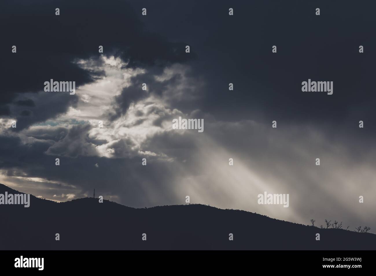 Intense Sun Rays thick stormy clouds over the mountains with intense sun rays peaking ...