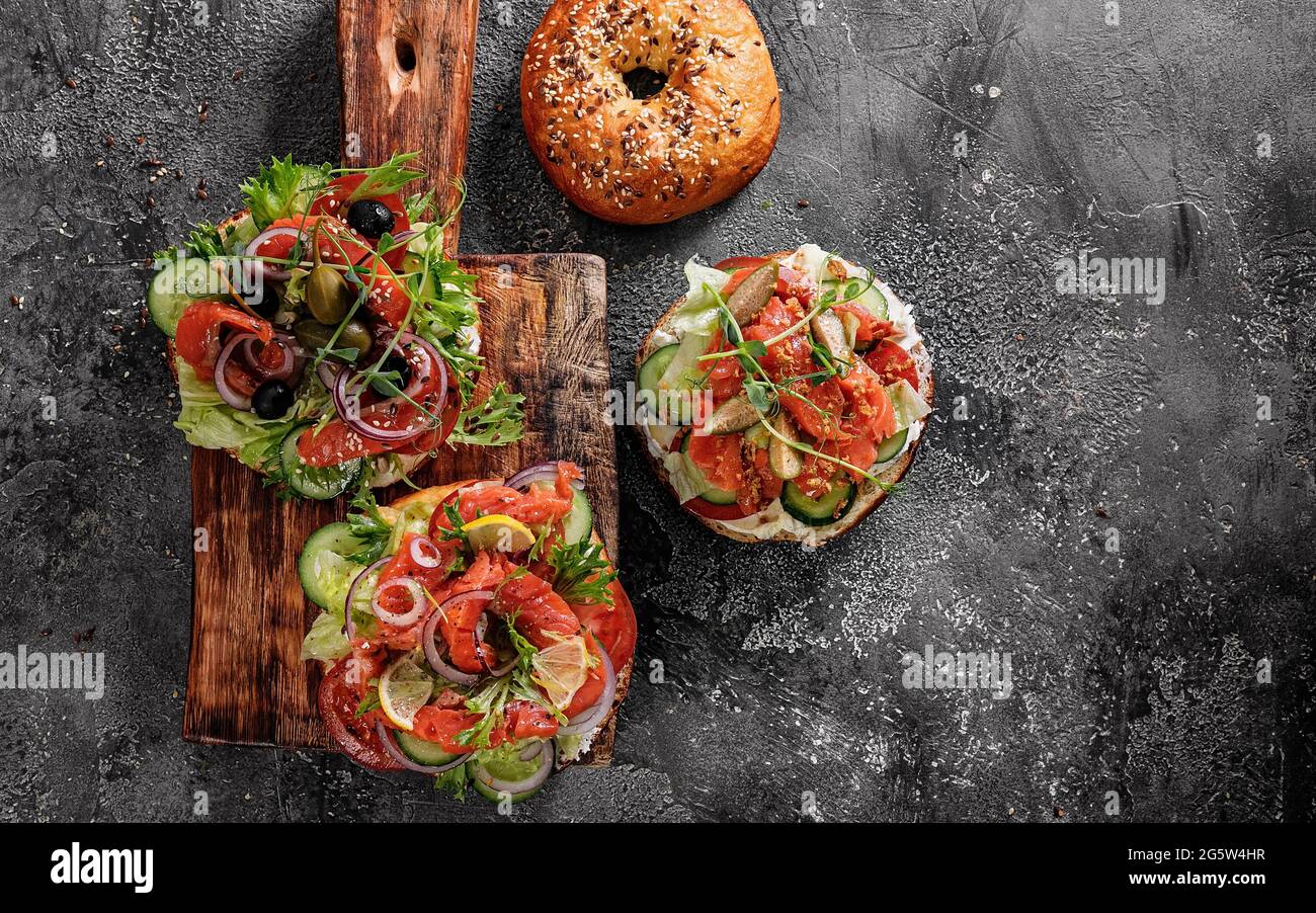 Sandwich salad New York bagel with cream cheese, lettuce, cucumber, herbs, capers, onions and salted red fish. Excellent delicious breakfast or snack Stock Photo