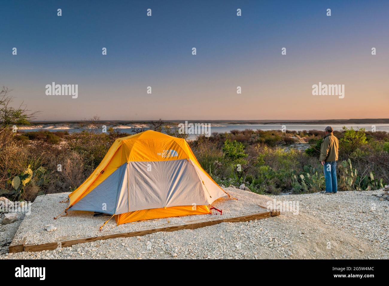 Camper looking at Amistad Reservoir at sunrise, Governors Landing campground, near Del Rio, Texas, USA Stock Photo