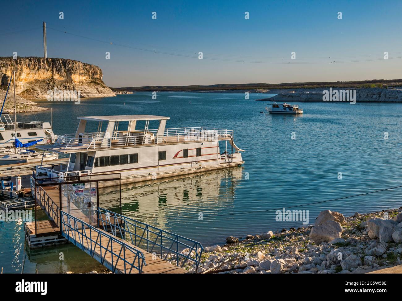 Boats moored at marina near Rough Canyon Cliffs, Amistad Reservoir, sunset, near Del Rio, Texas, USA Stock Photo