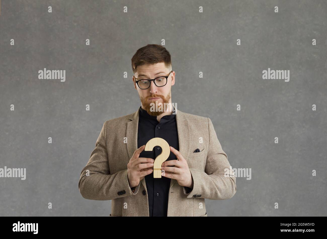 Confused man with question mark thinking of business solution or answer to difficult question Stock Photo