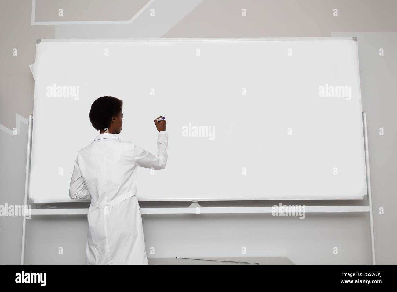 African American black woman math teacher writing on empty white board ...