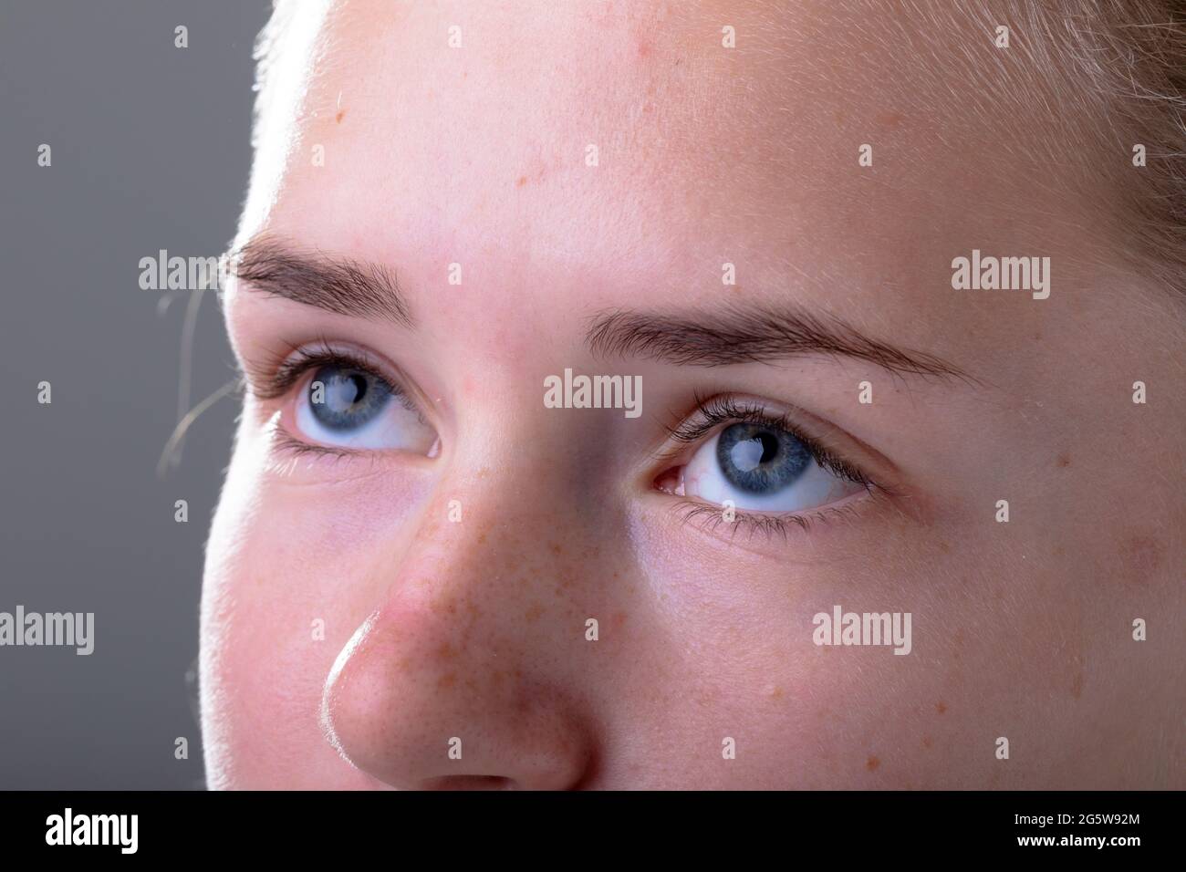 Close up of blue eyes of caucasian businesswoman, isolated on grey background Stock Photo