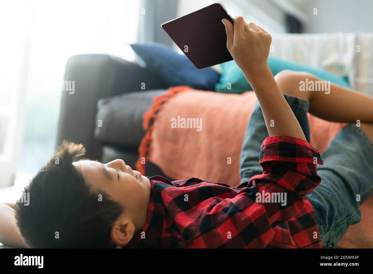 Asian boy using tablet with blank screen lying on floor at home Stock Photo