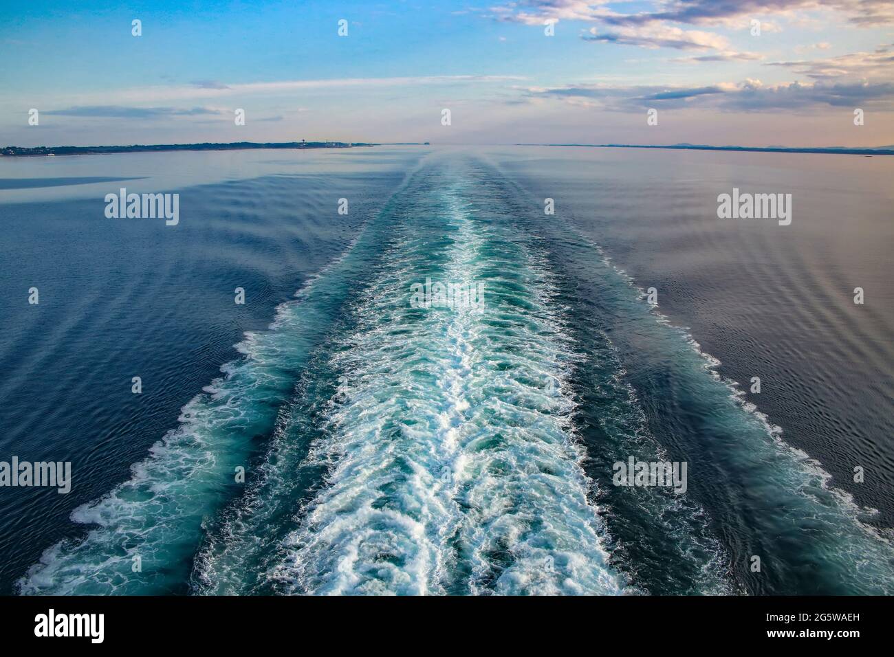 Wake of a ship across Ocean while sailing the Baltic, on a beautiful day. Purple and blue light reflecting on the sea and waves. Stock Photo