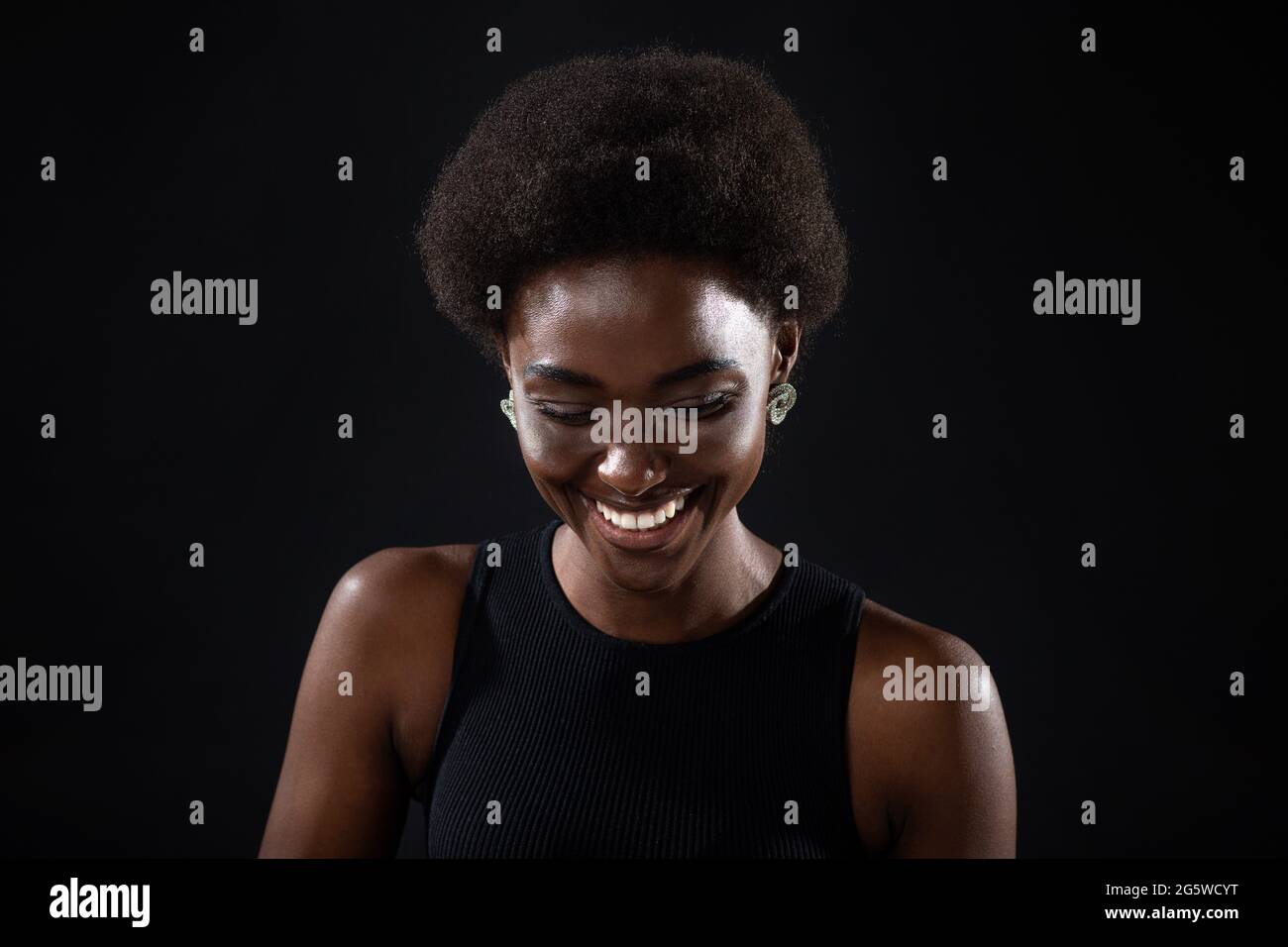 Young black positive african american woman laughing portrait on black background Stock Photo