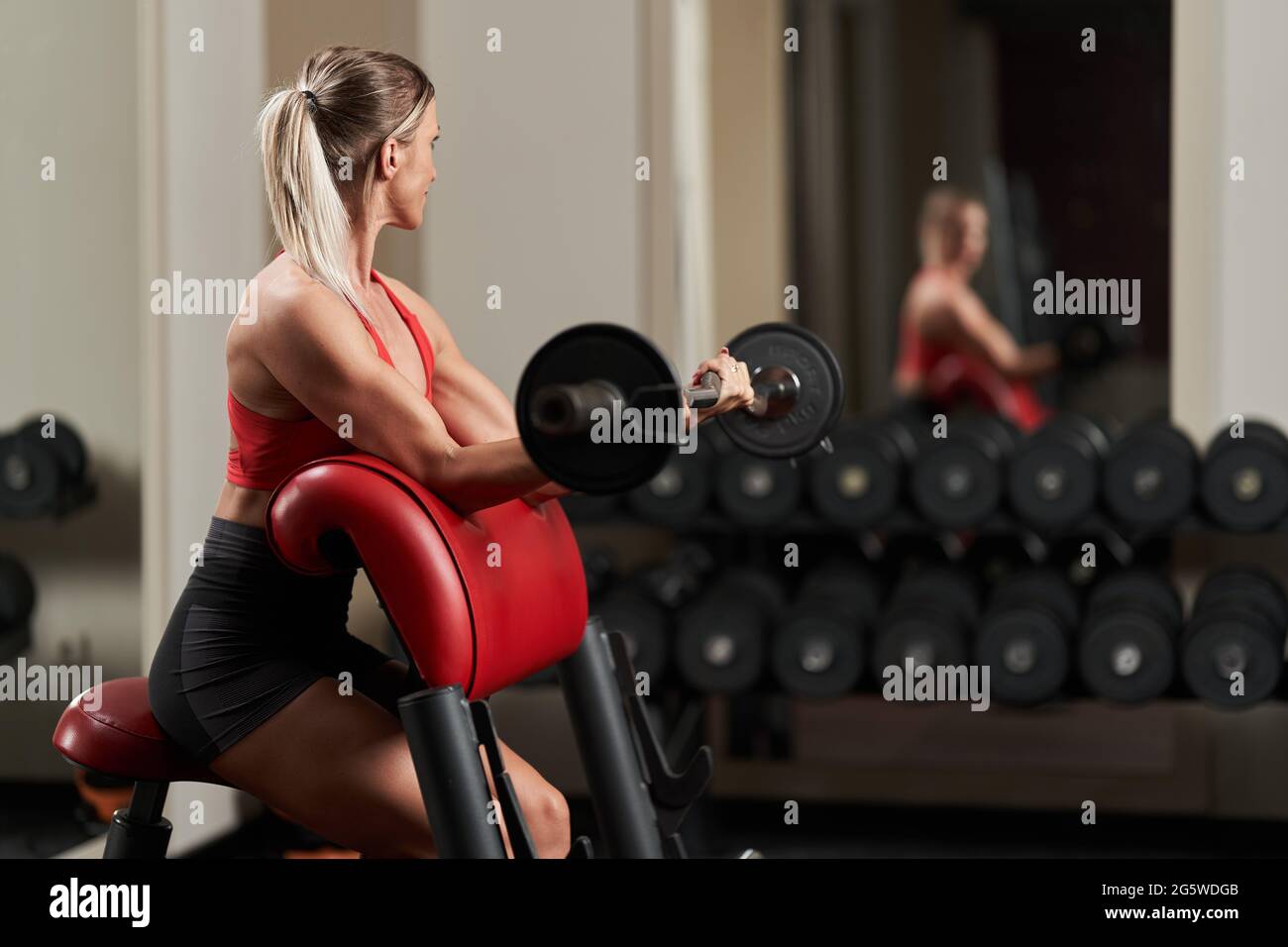 Fitness woman doing biceps curls with a curved barbell in the gym Stock Photo Alamy