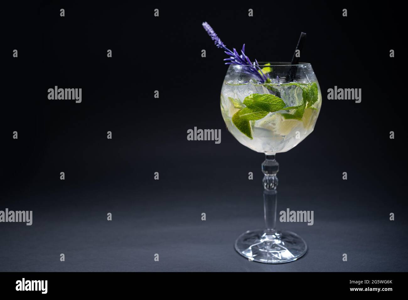 cocktail hugo or mojito with mint, lime and ice in wineglass on black background Stock Photo