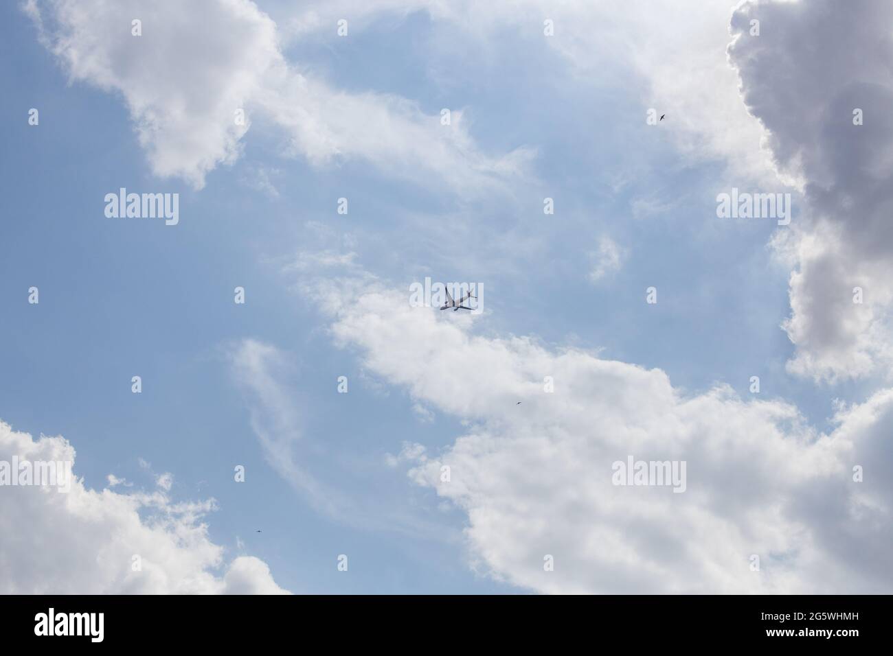 Propeller plane lit by the sun against a blue sky with white clouds and ...