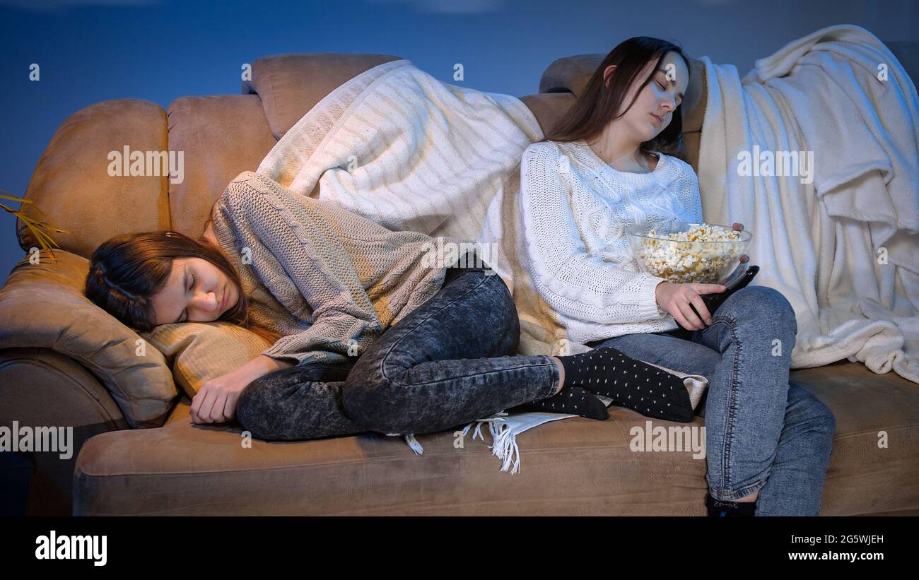 Young friends fell asleep while watching TV show on sofa at night Stock