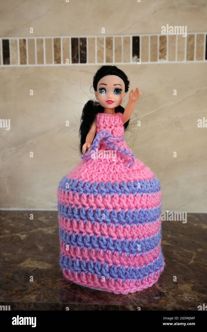 Toy doll with crochet dress which extends over a fresh roll of