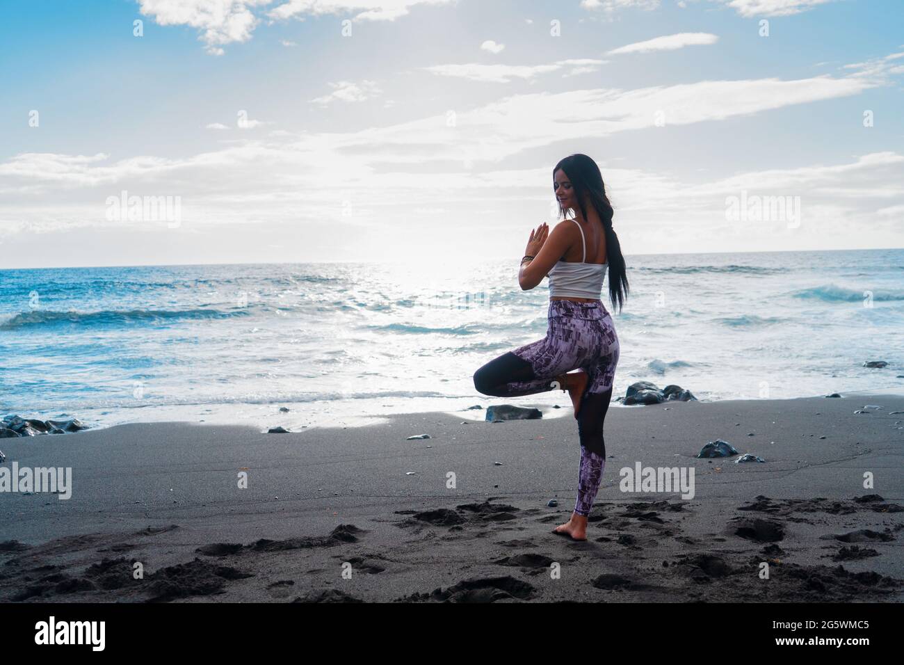 woman in sport clothes practicing yoga and meditating on beach in morning Stock Photo
