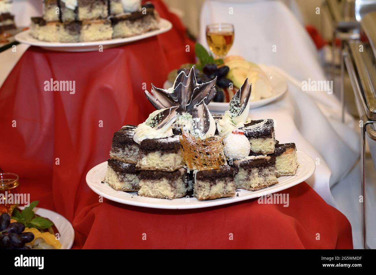 Catering plate on a red tablecloth with small brown and white cakes decorated with both white and dark chocolate Stock Photo