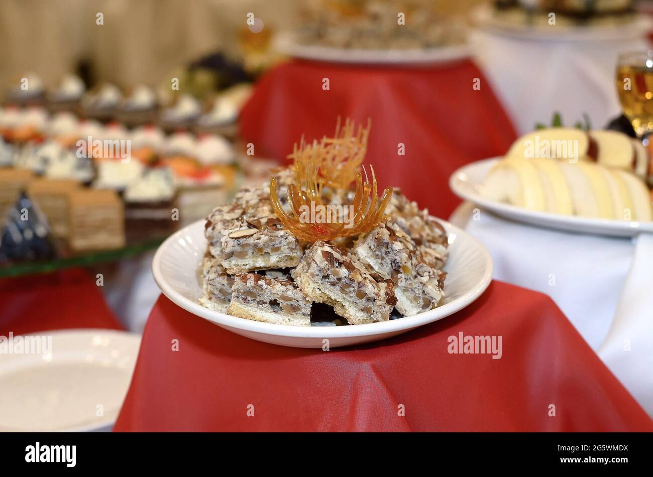 Catering a plate on a red tablecloth with small cakes made of different nuts and peanuts decorated with caramel Stock Photo