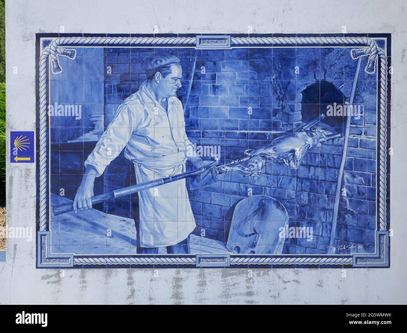 Vintage Blue tile azulejos depicting a cook putting meat to roast in wood oven on a mural in Mealhada, Portugal Stock Photo