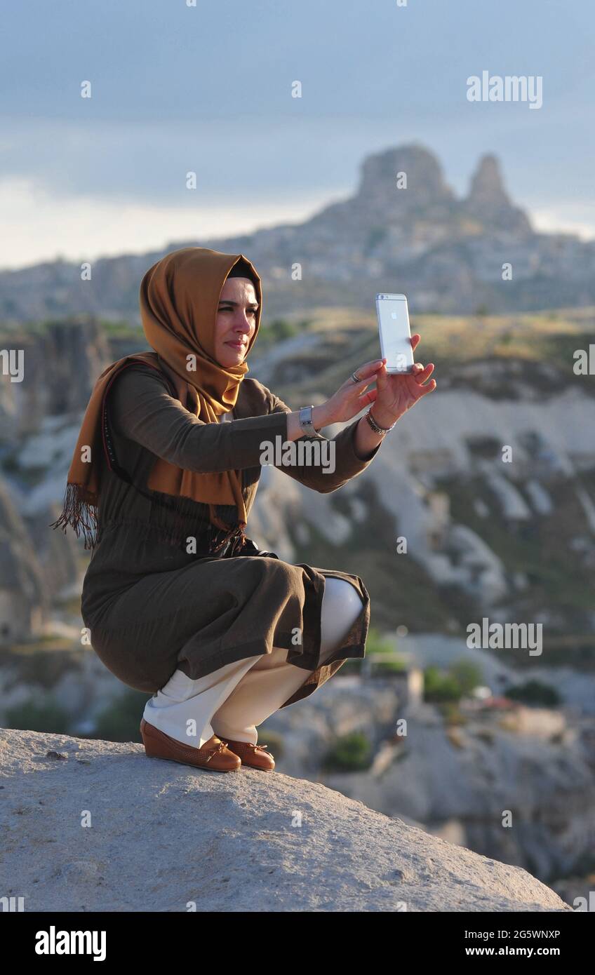 TURKEY. CAPPADOCIA. WOMAN DOING A SELFIE IN FRONT OF THE VILLAGE OF UCHISAR. Stock Photo