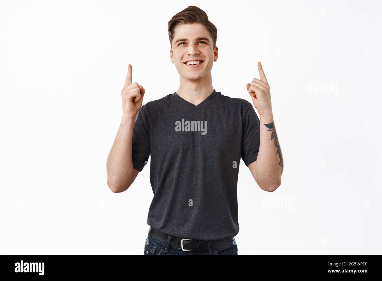 Smiling satisfied man looks and points up, stare happy and pleased at ...