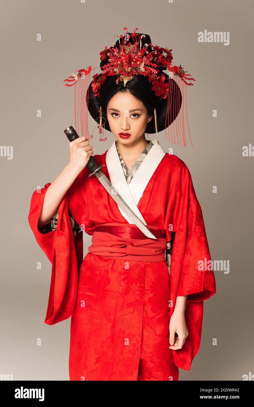 Asian woman holding sword and looking at camera isolated on grey Stock Photo