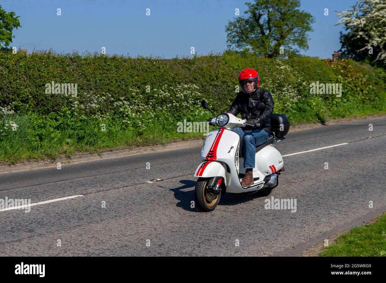 2020 White Vespa city traffic Racing Sixties a special edition retro style scooter with red and gold graphics and gold-coloured wheels travelling in Cheshire, UK Stock Photo