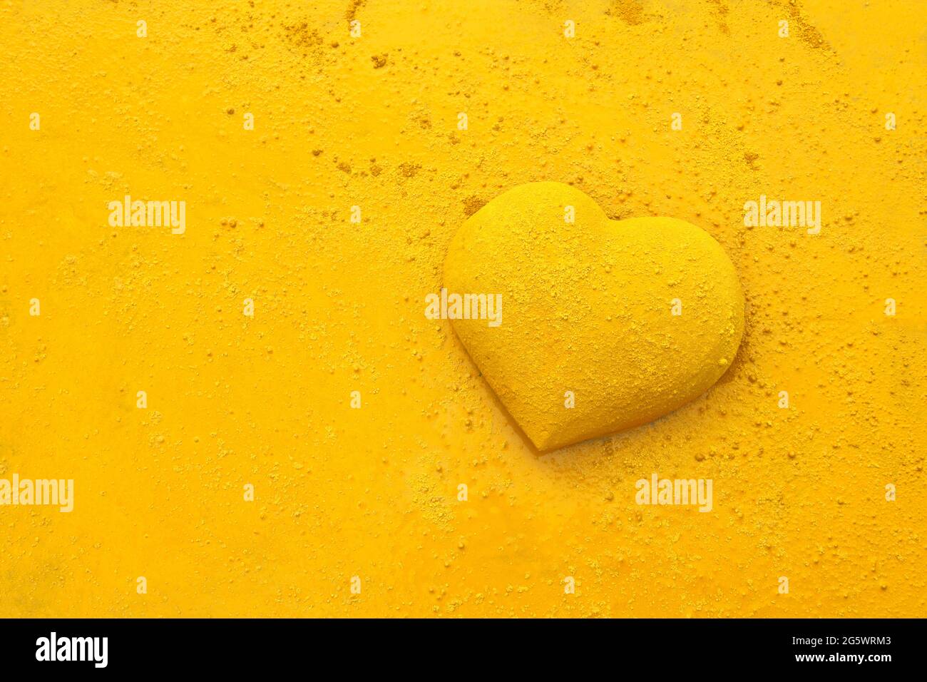 3 dimensional heart shape splattered by yellow paint, and sprinkled with dry pigment.   The paint used is Gerstaecker Creativ Pigmente (Gerstaecker Cr Stock Photo