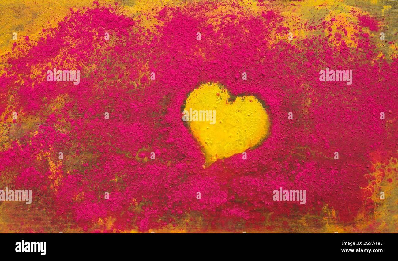 Yellow heart shape surrounded by red powdered paint pigment. Stock Photo