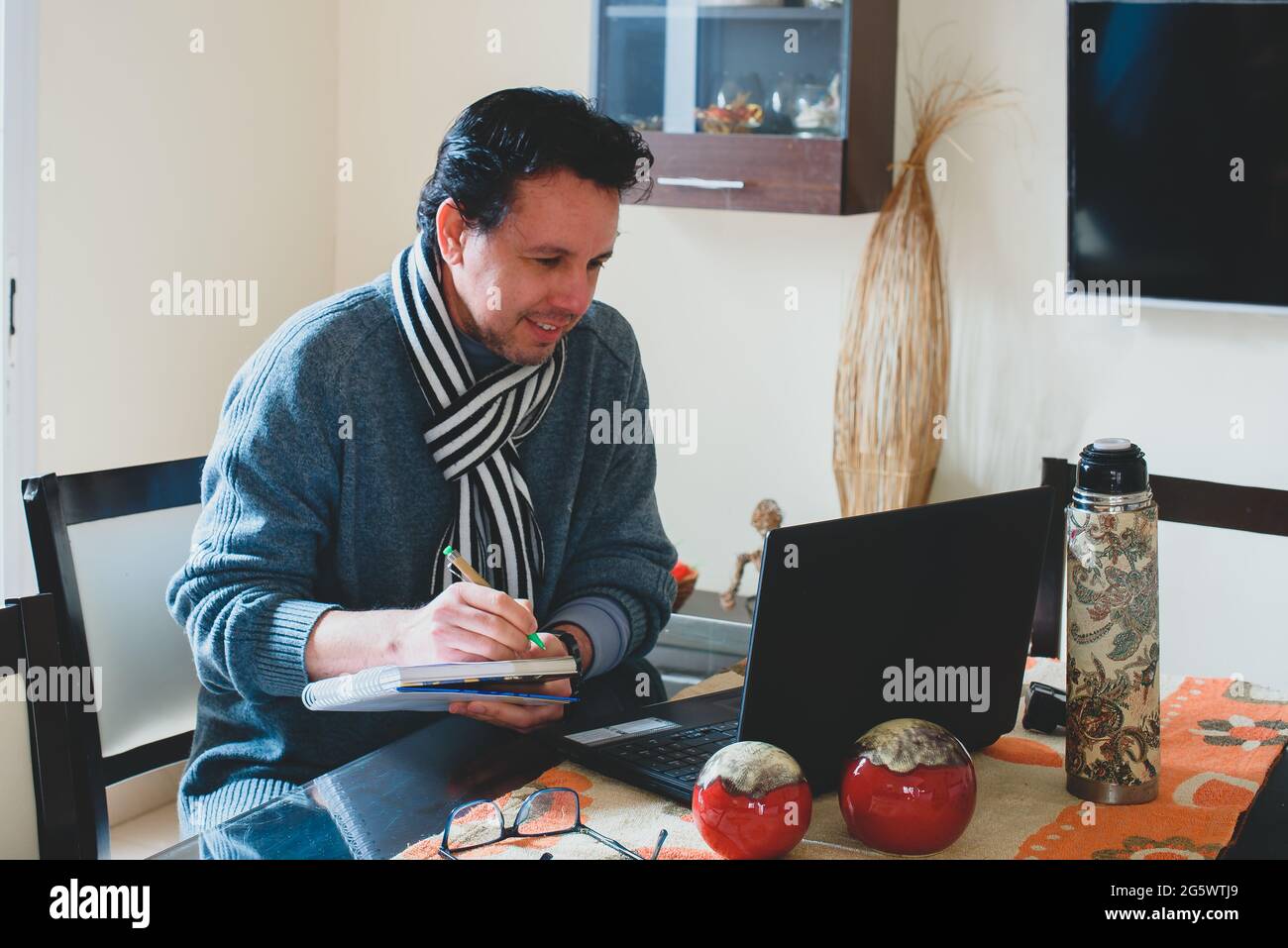 Hombre escribiendo en la mesa de madera planificando el analisis de negocio con la laptop, venta,compra, internet desde casa. Stock Photo