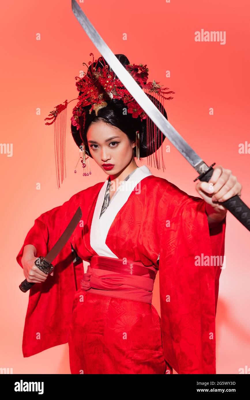 Japanese woman holding swords on red background Stock Photo