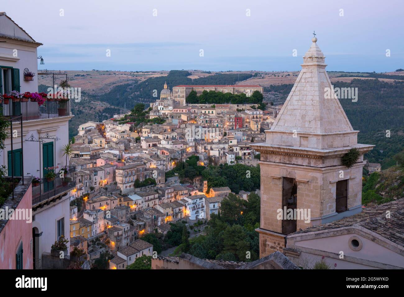 Ragusa, Sicily, Italy. View across valley to the rooftops of Ragusa Ibla, dusk, bell-tower of the Church of Santa Maria delle Scale in foreground. Stock Photo