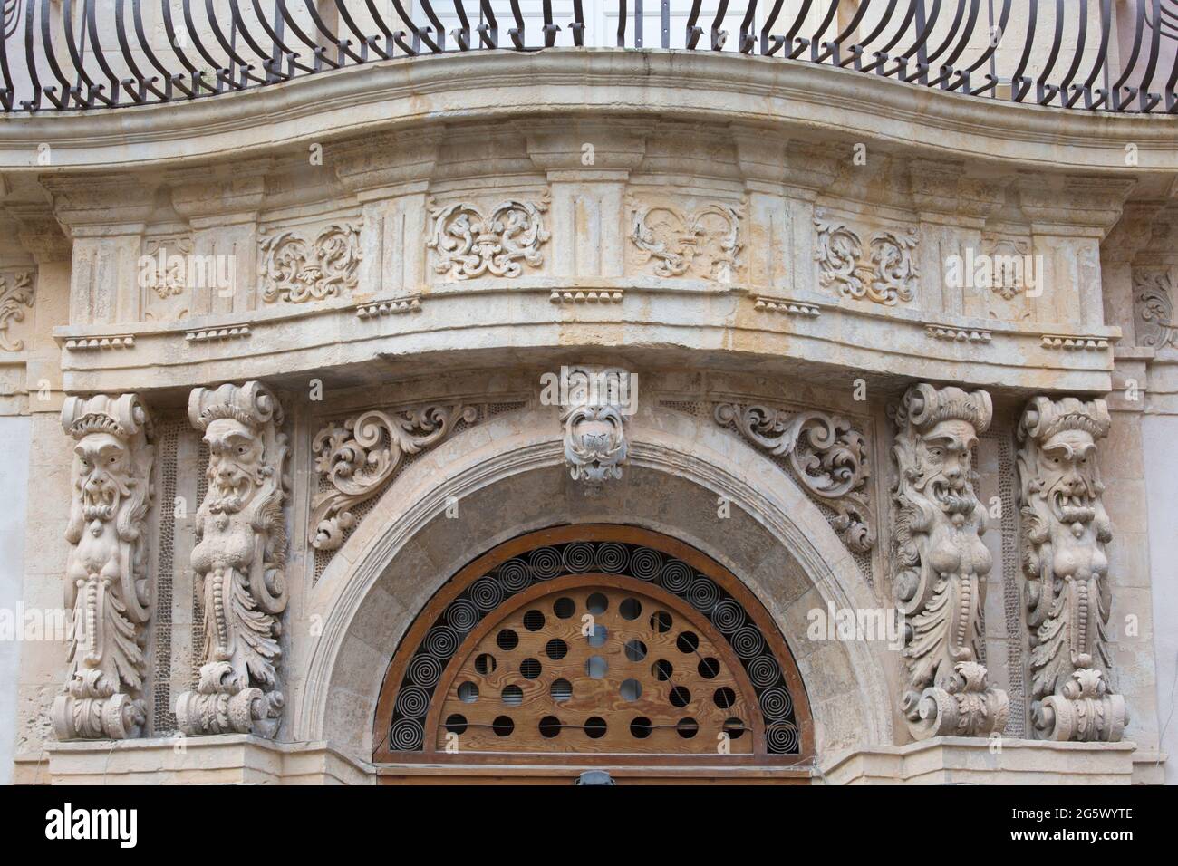 Noto, Syracuse, Sicily, Italy. Grotesque carved figures on flamboyant ornamental façade of a historic baroque palazzo in Corso Vittorio Emanuele. Stock Photo