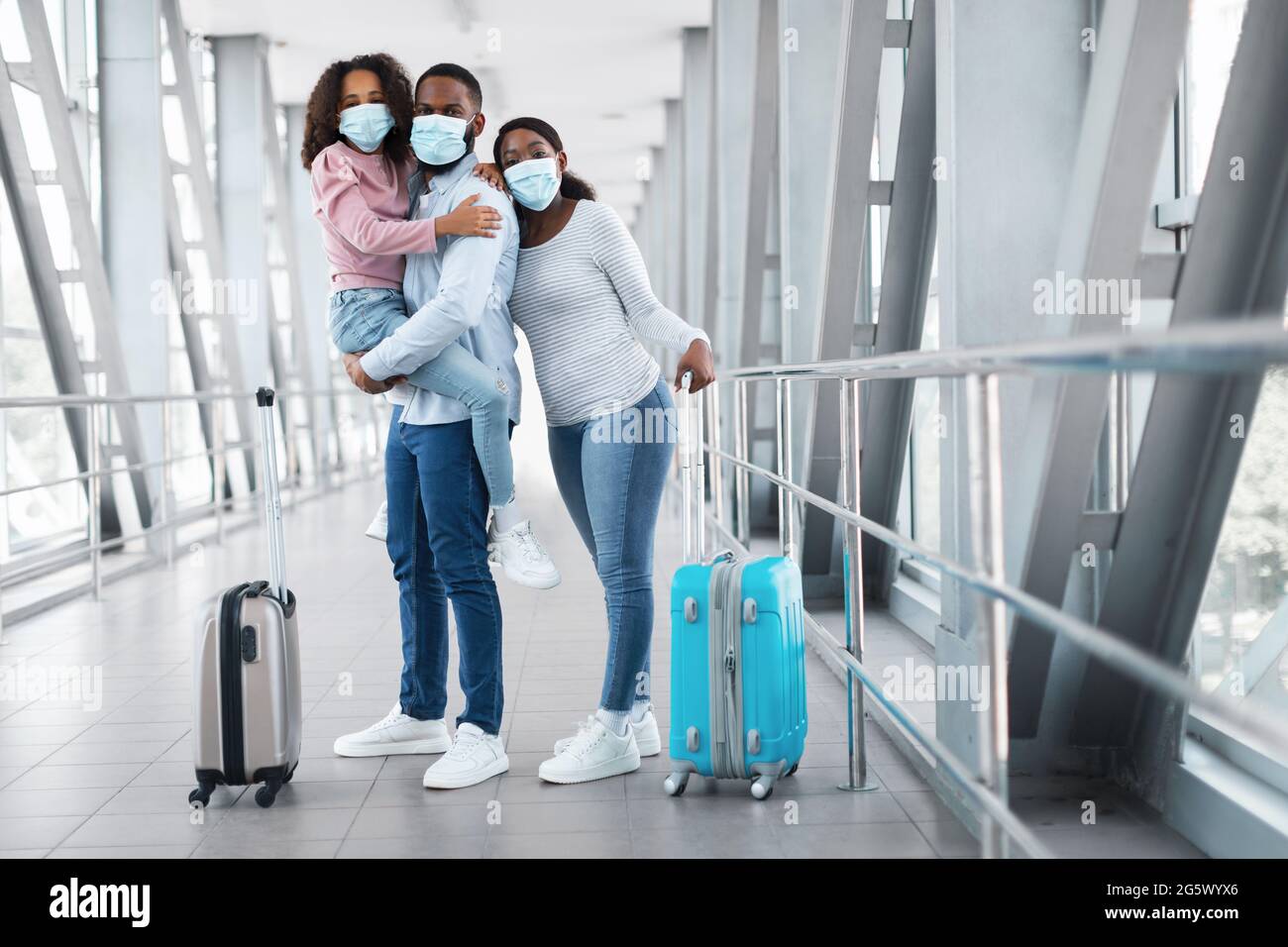 Happy african family traveling with daughter, standing in airport Stock