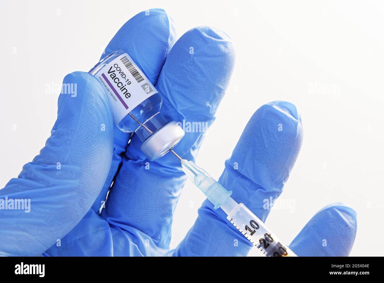Close-up of hand in nitrile gloves holding covid-19 vaccine vial and extracting fluid with syringe for injection. Healthcare, medicine pharmacy and va Stock Photo