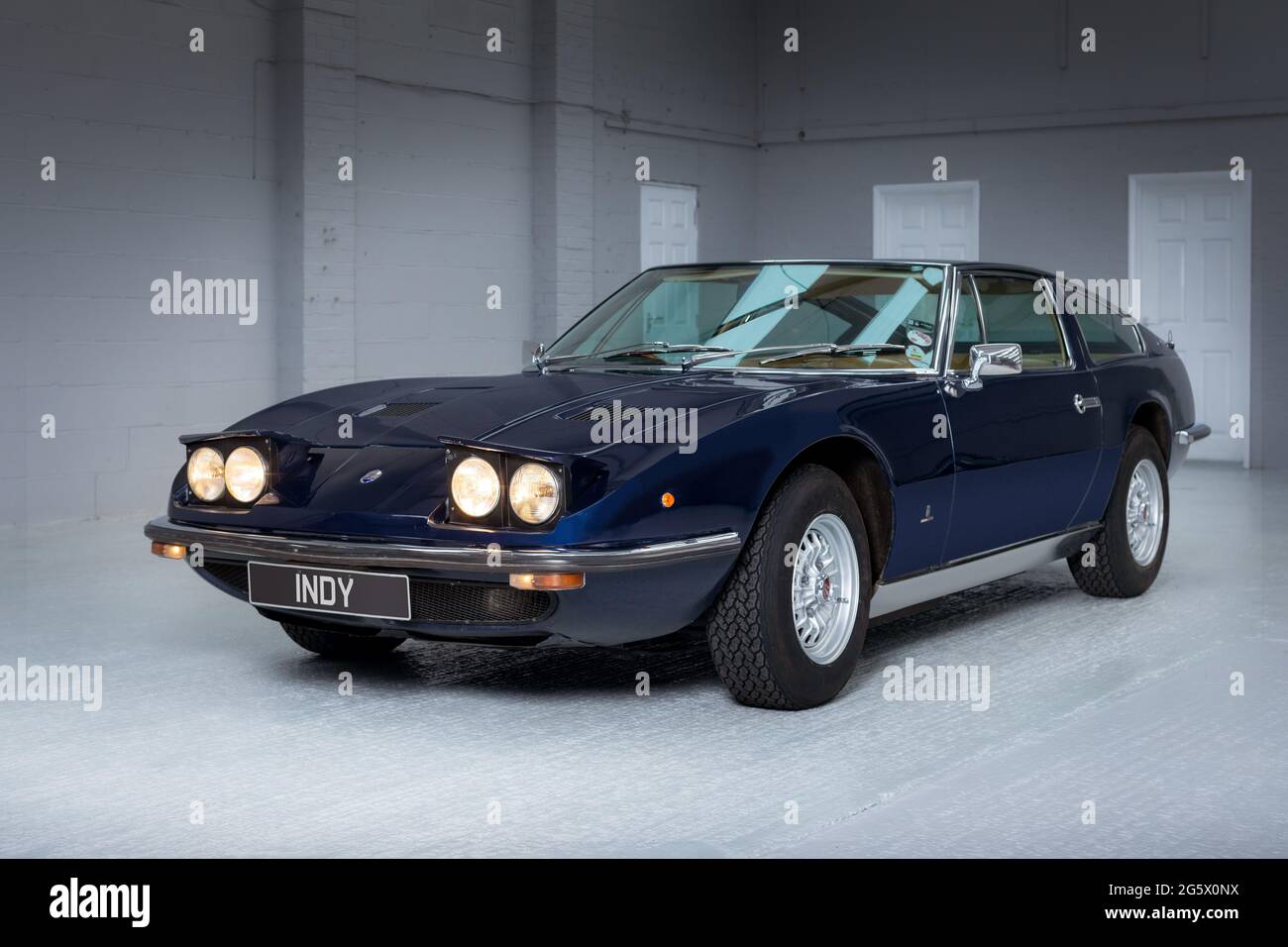 Quarter front view showing pop-up headlights of a blue 1971 Maserati 4700 Indy America V8 - Stock Image