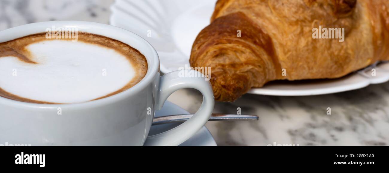 Classic Italian breakfast Cappuccino and Cornetto on marble table in a Bar Stock Photo