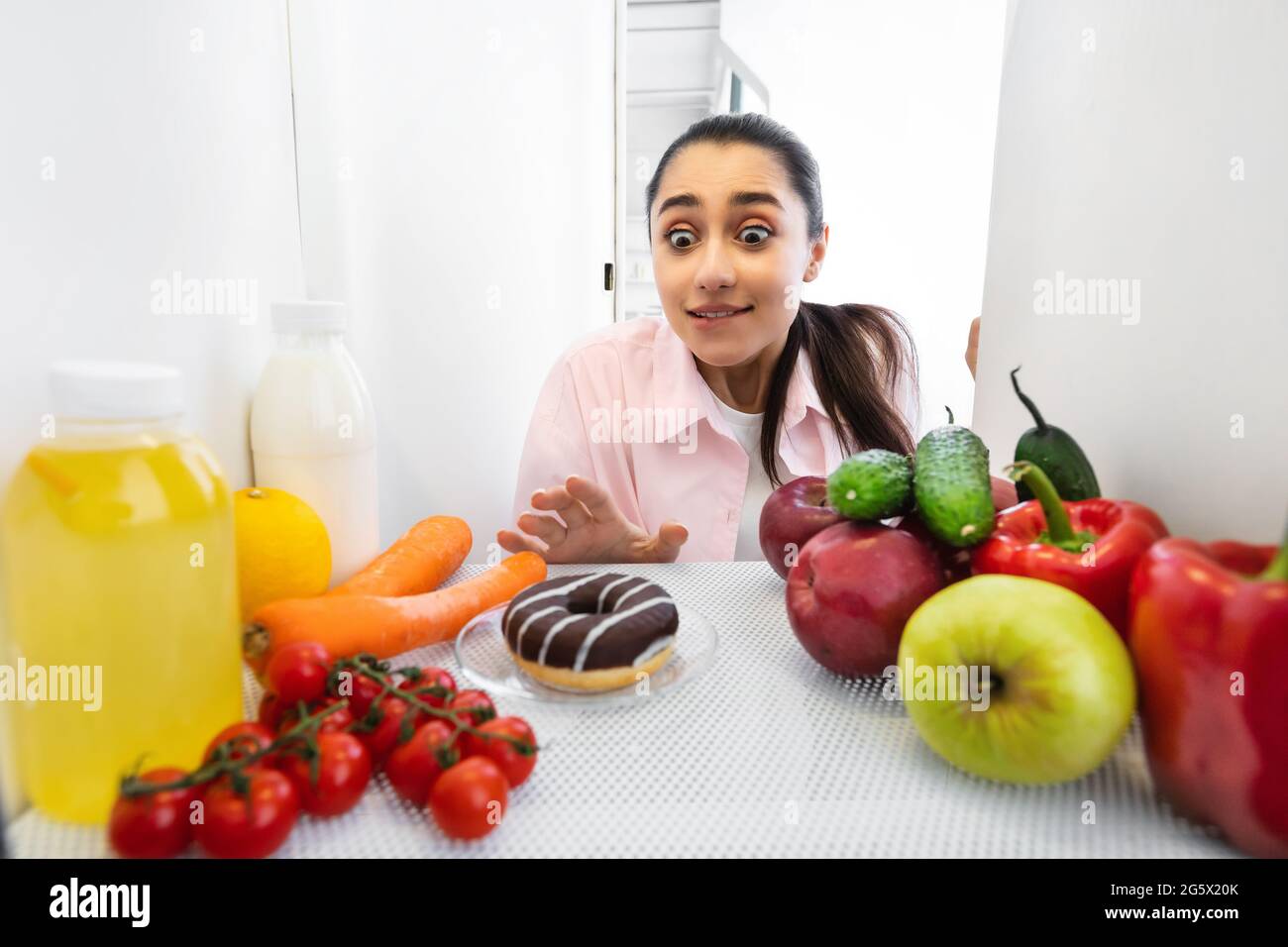 Excited funny woman looking at yummy donut view from fridge Stock Photo